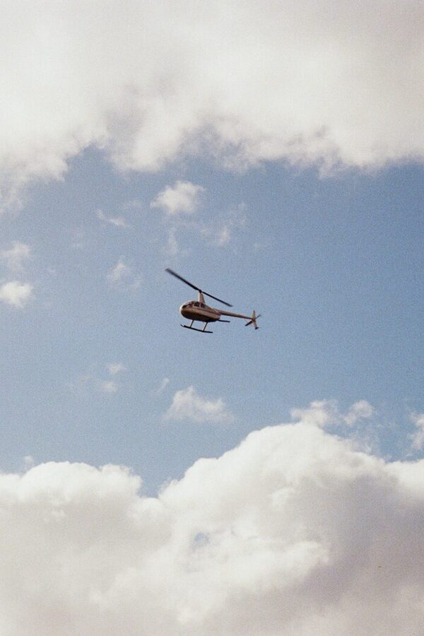 A helicopter flying among white clouds in a blue sky
